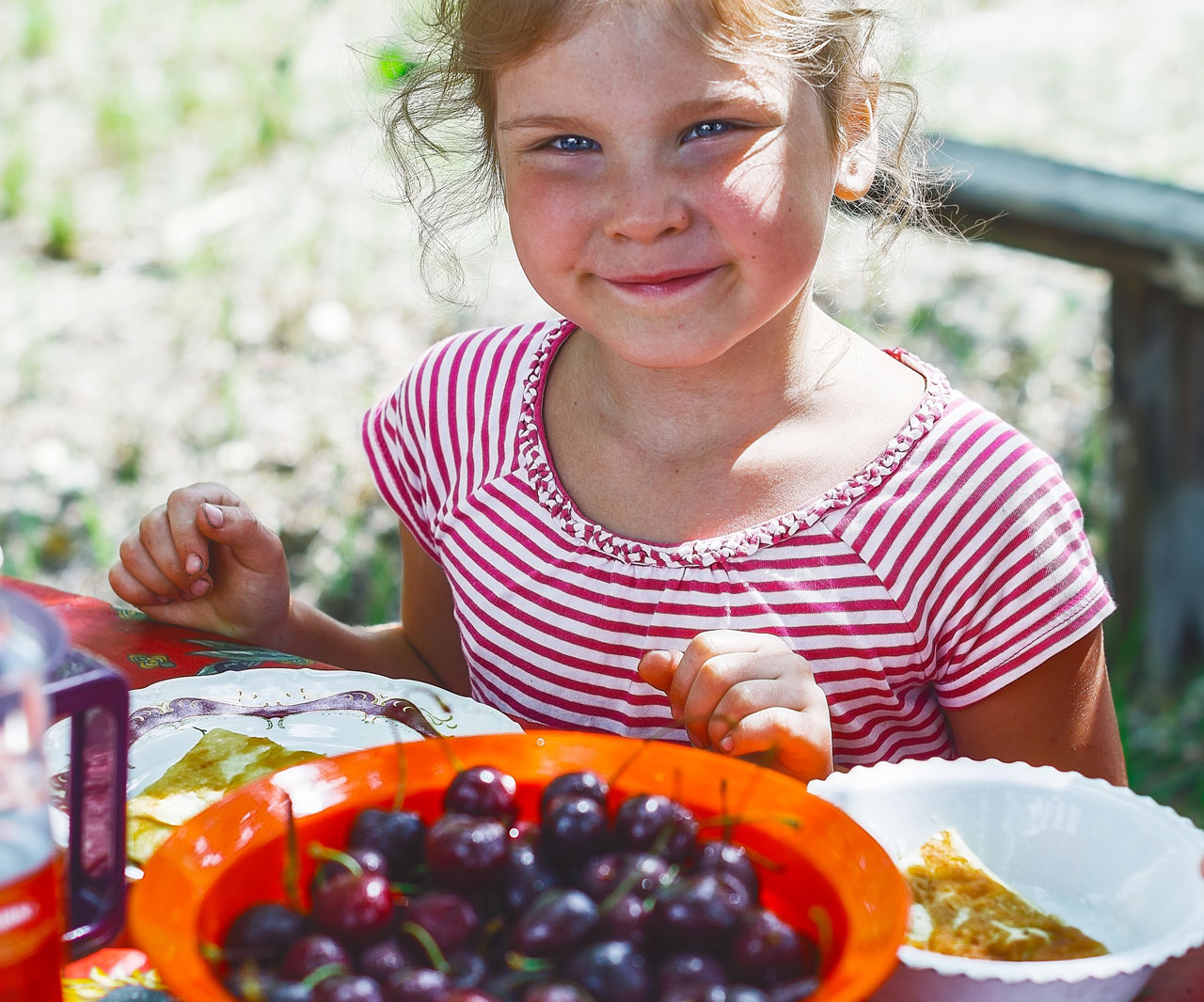 Child sitting in front of a bowl of fruit.