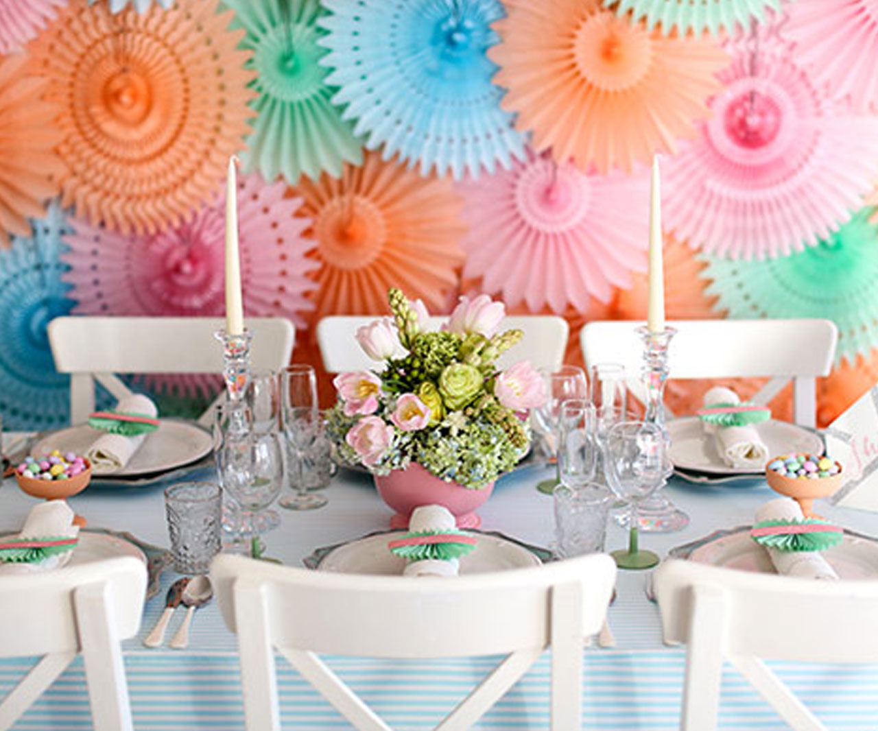 Table set up for a party with flowers and a decorative backdrop.