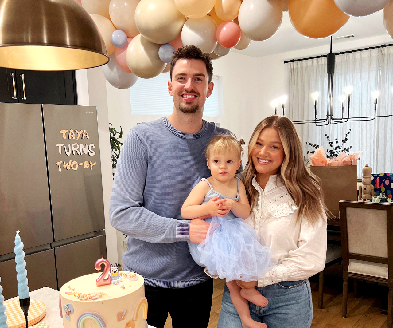 Taya and her parents at Taya's birthday party smiling.