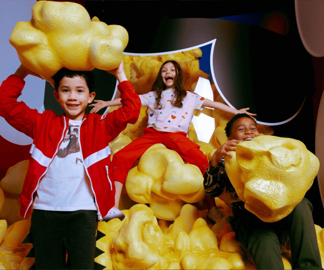 Kids holding giant fake popcorn pieces.