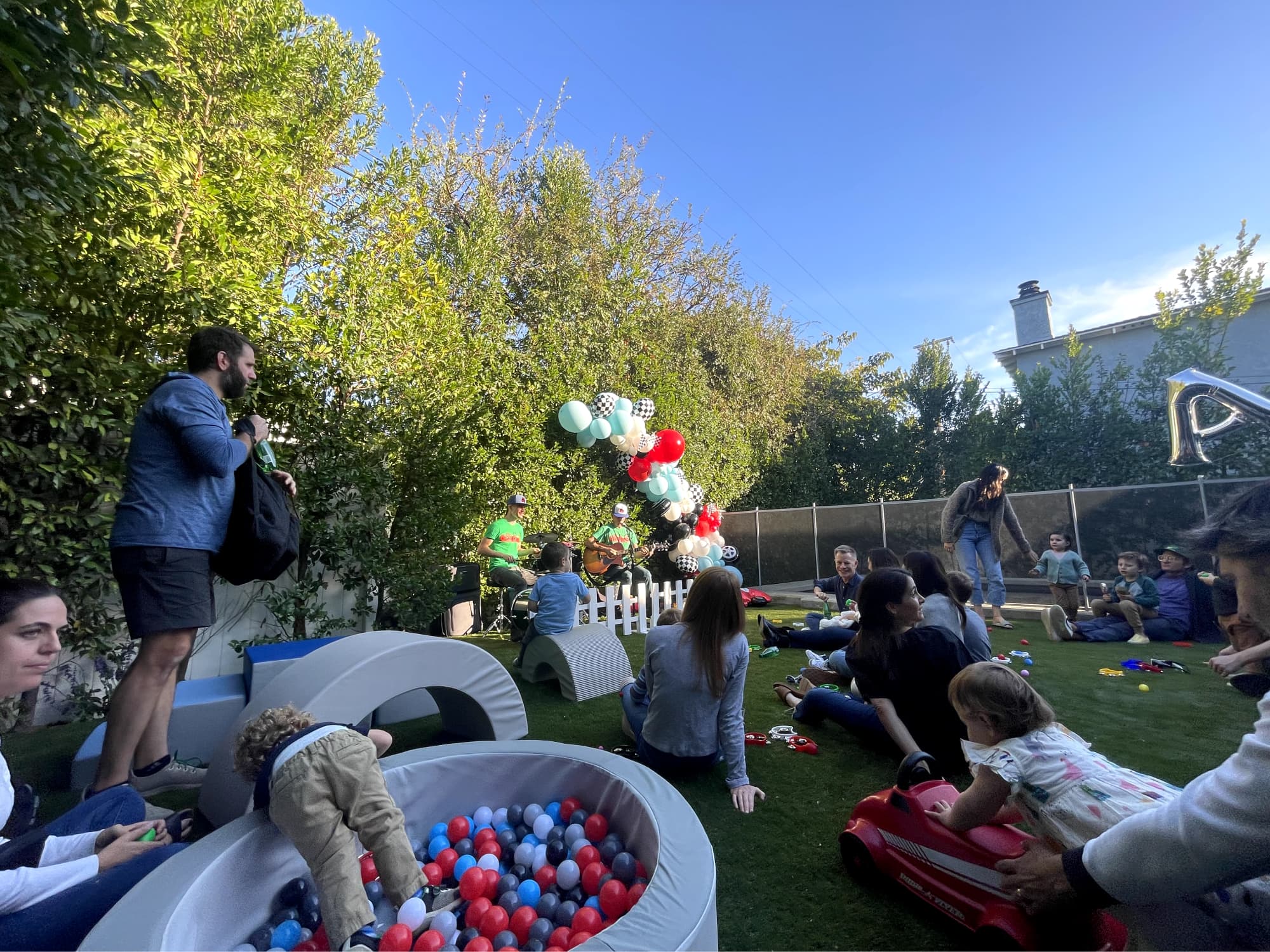 Kids playing in ball pit and with toy cars at a car-themed birthday party.