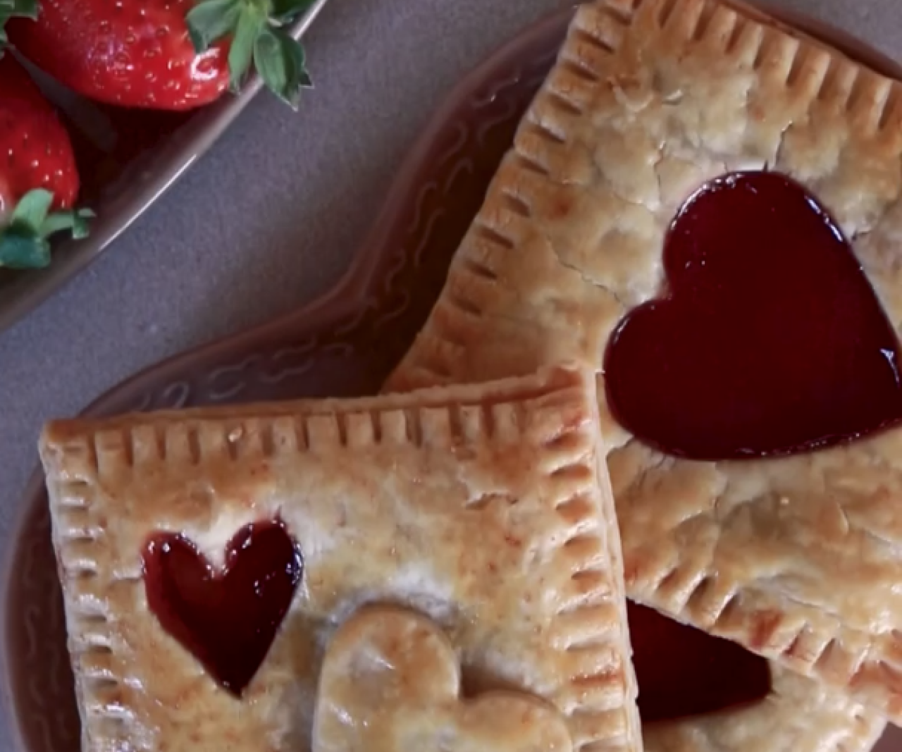 A plate of jam hand pies with heart-shaped cut outs.