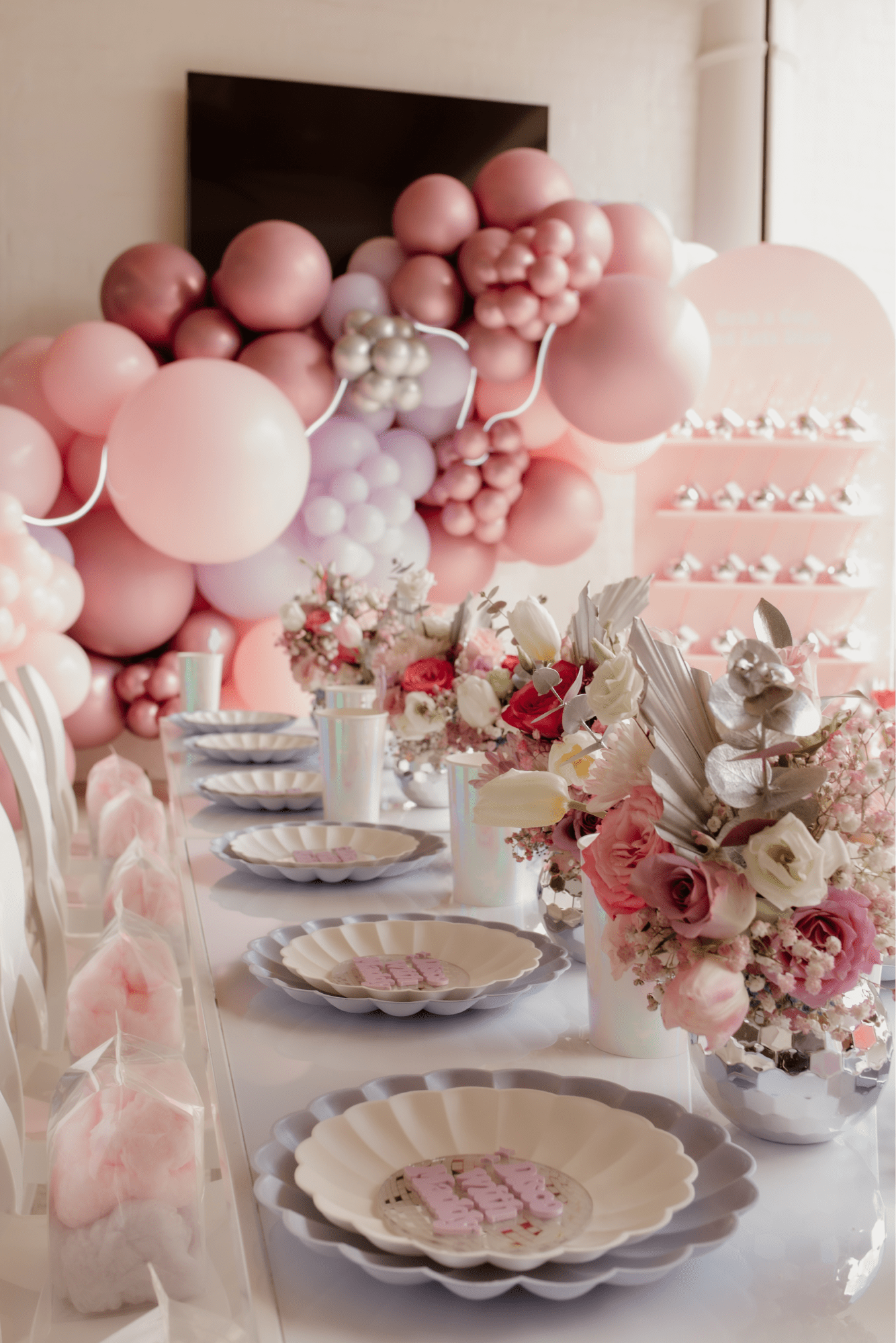 A table set with flowers, plates, and cotton candy.