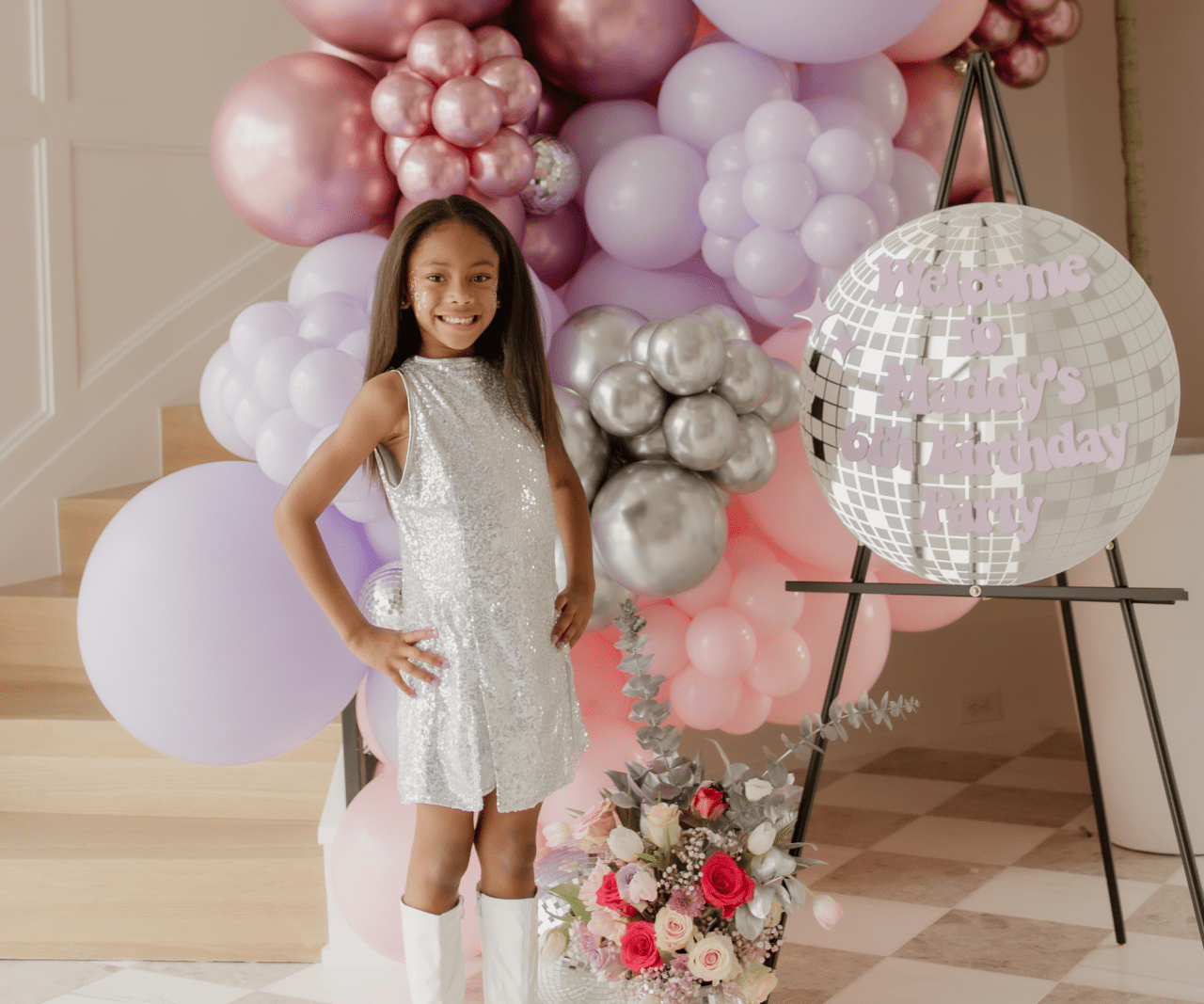 Birthday girl poses in a sequin dress in front of balloons.