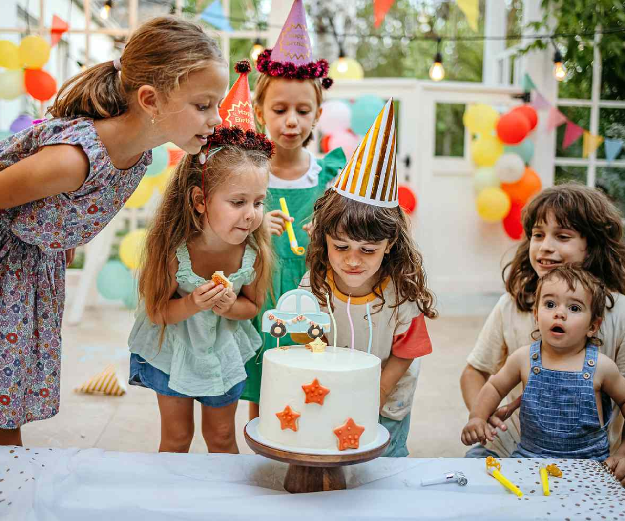 Kids at a birthday party blowing out candles.