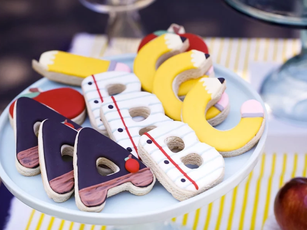 A plate of ABC cookies decorated like chalkboards, notepads and pencils.