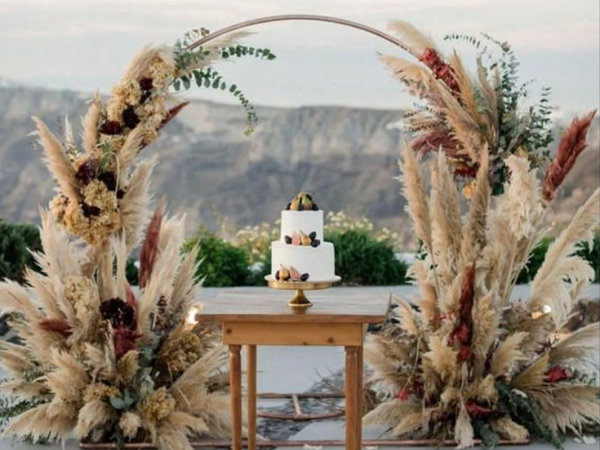 Pampas grass-covered circle frame with a wedding cake (image from Pinterest).