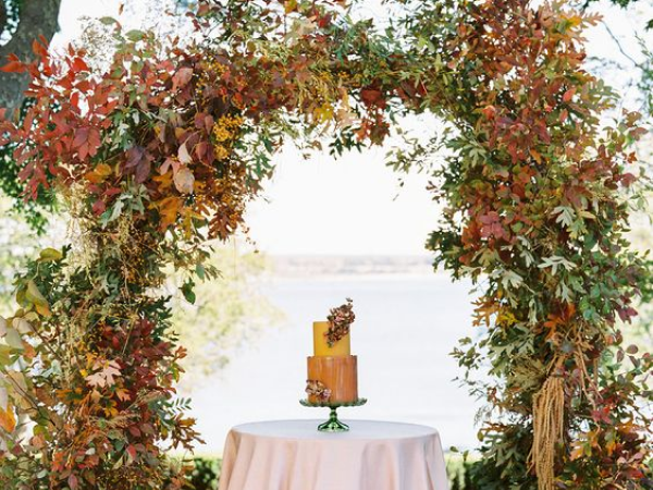 Wedding cake with a fall foliage arch over it (image from Pinterest).