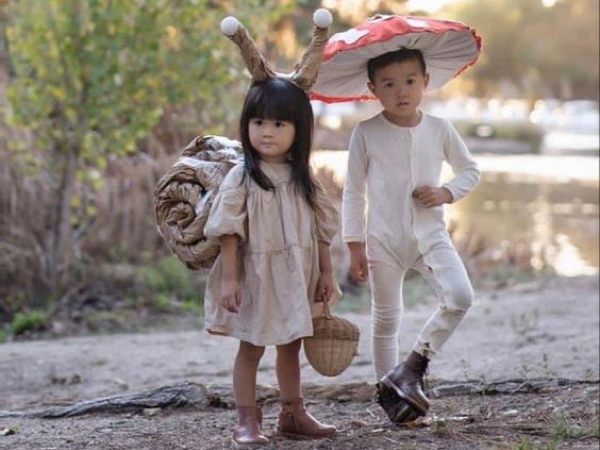 Child dresses as a mushroom next to another child dressed as a snail. 