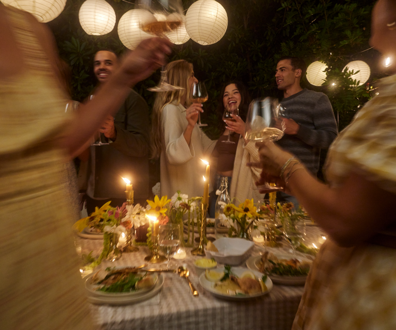 People celebrating at an outdoor Friendsgiving dinner.