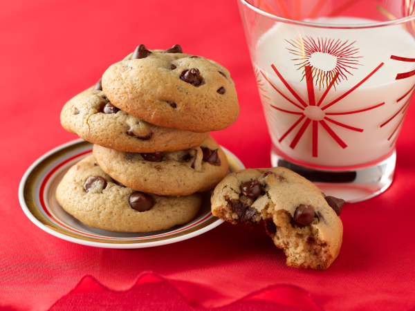 A pile of chocolate chip cookies and a glass of milk.