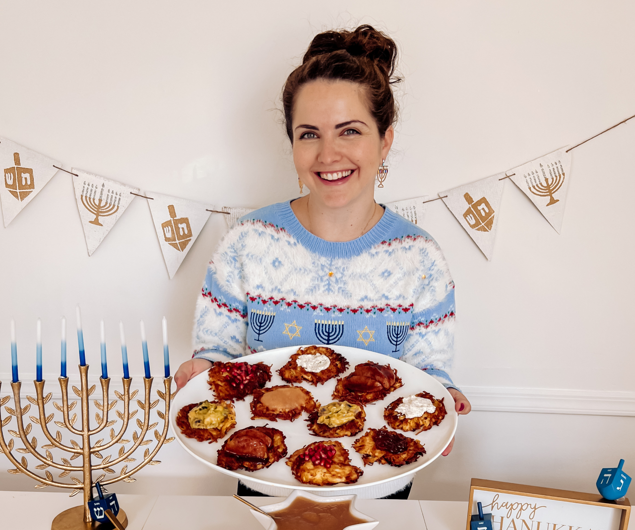 Ariel holding a platter of latkes with various toppings.