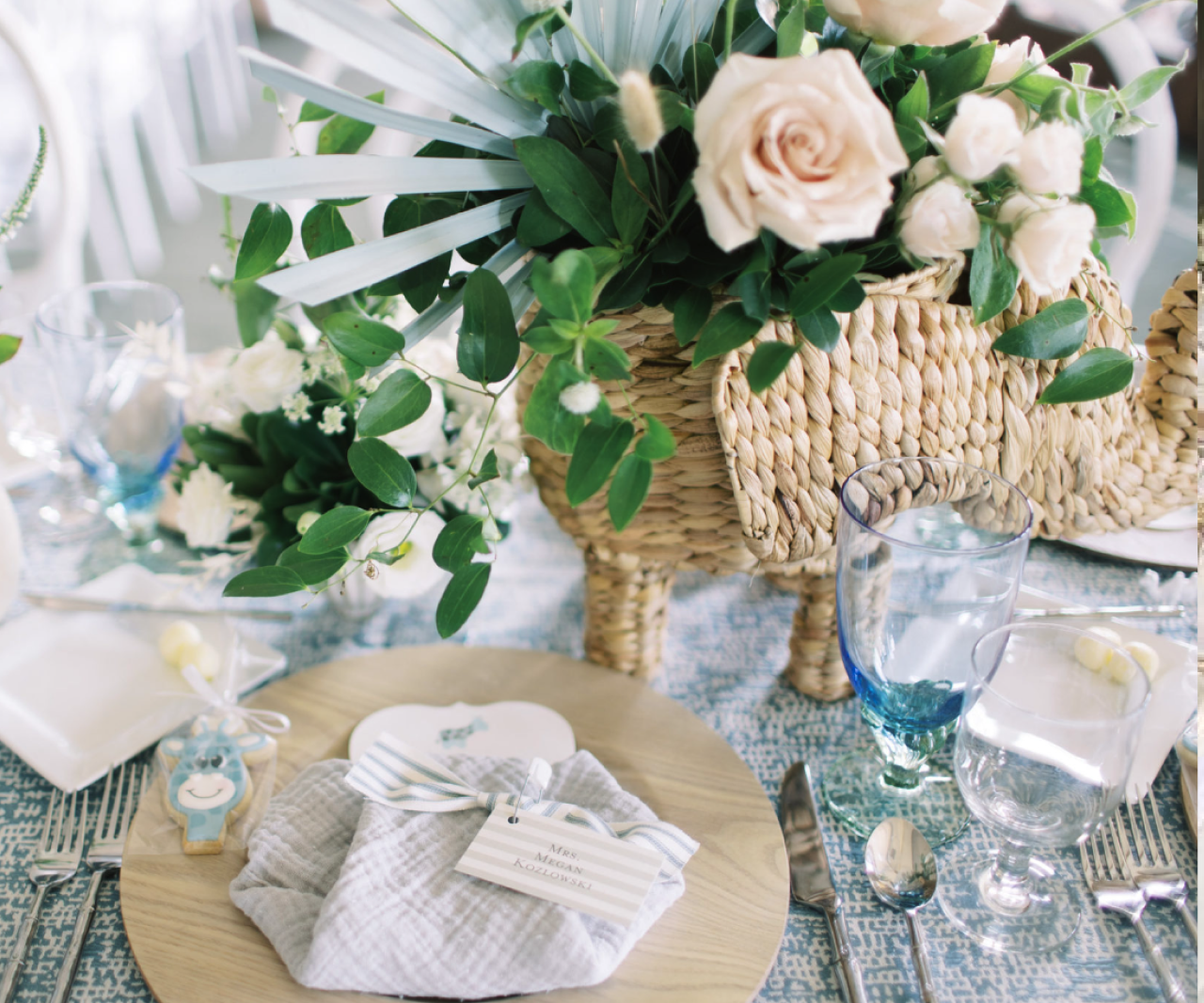 Baby shower tablescape with a cute elephant planter, glasses and party favors.