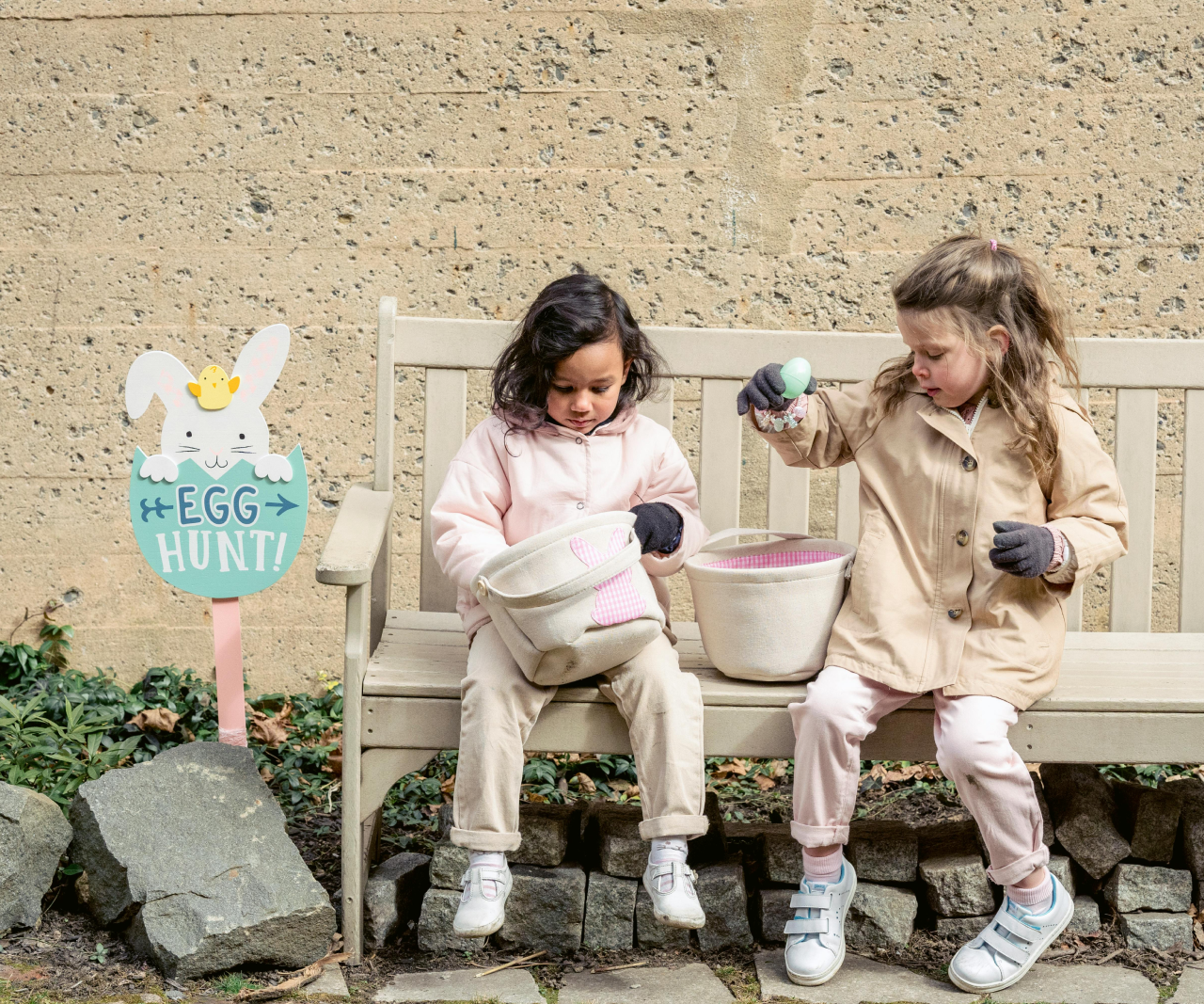 Two kids sitting on a bench looking at items in Easter baskets.