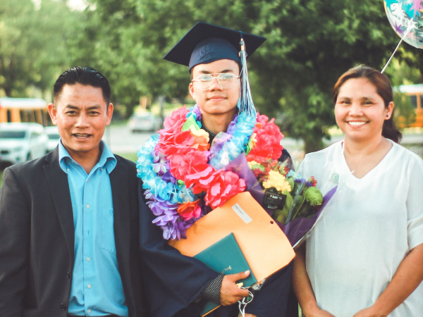 A graduate in his cap and gown surrounded by his family.