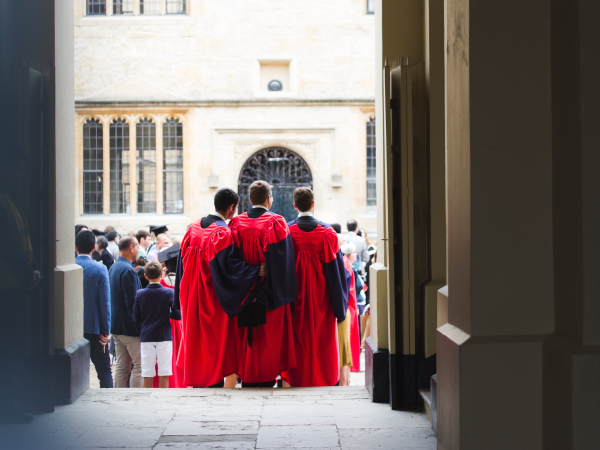 A trio of graduates facing away from the camera with their arms around each other.